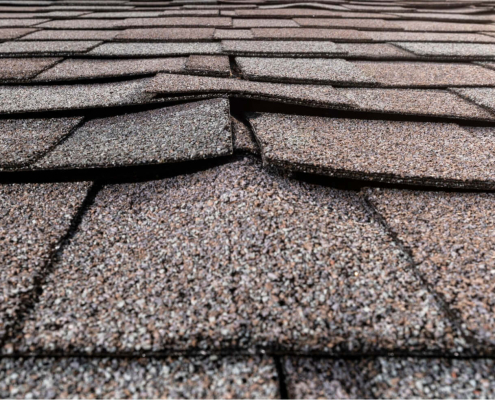 A photo showing various types of buckled shingles on a roof