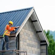 How Regular Roof Care Helps Westminster Homes Last Longer and Save on Repairs 3 A construction worker in an orange vest and hard hat is actively working on a residential building.