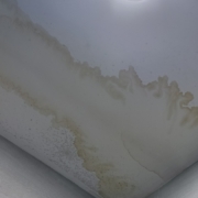 Brown water stain spreading across a bathroom ceiling corner