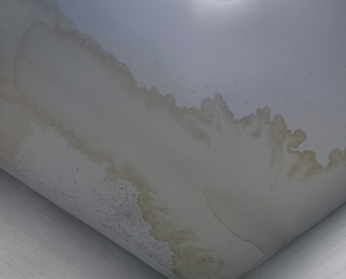 Brown water stain spreading across a bathroom ceiling corner