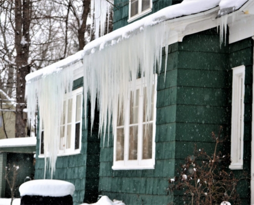 Ice Dams on the Shore: Why Beach Homes Get Winter Leaks 2 Ice dam with long icicles hanging from the eave of a shore house in winter, Ocean City MD