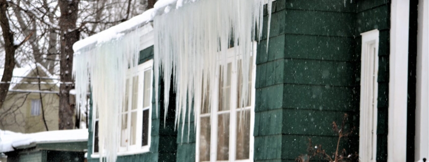 Ice Dams on the Shore: Why Beach Homes Get Winter Leaks 1 Ice dam with long icicles hanging from the eave of a shore house in winter, Ocean City MD