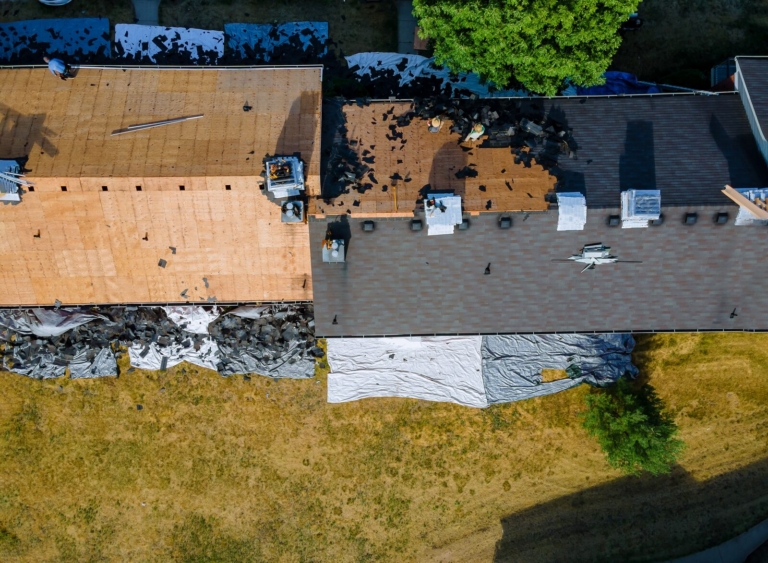 Aerial view of an old asphalt shingle roof being stripped down to the decking