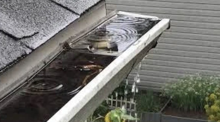 Gutter filled with rainwater overflowing over its edge during a storm